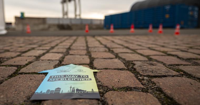 Wegweiser auf Kopfsteinpflaster mit der Aufschrift „Hier entlang zu MS Bleichen“ und dem Logo der ContainerDays Hamburg 2026, der die Besucher zum Veranstaltungsort am Hafen führt