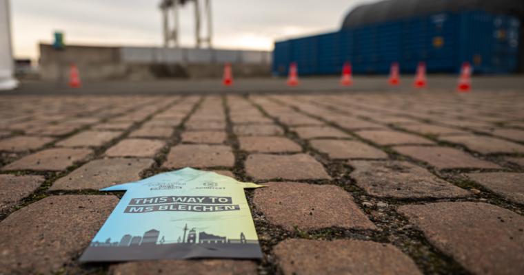 Wegweiser auf Kopfsteinpflaster mit der Aufschrift „Hier entlang zu MS Bleichen“ und dem Logo der ContainerDays Hamburg 2026, der die Besucher zum Veranstaltungsort am Hafen führt