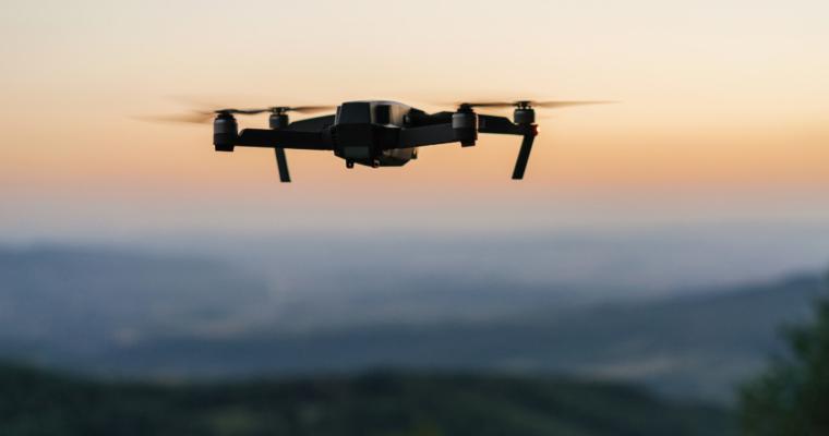 Eine Drohne fliegt in der Abenddämmerung über eine Berglandschaft