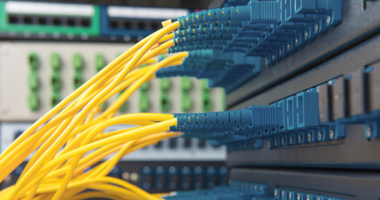 Gelbe Glasfaser-Patchkabel, die an blauen LC-Adaptern an einem Netzwerk-Patchpanel angeschlossen sind